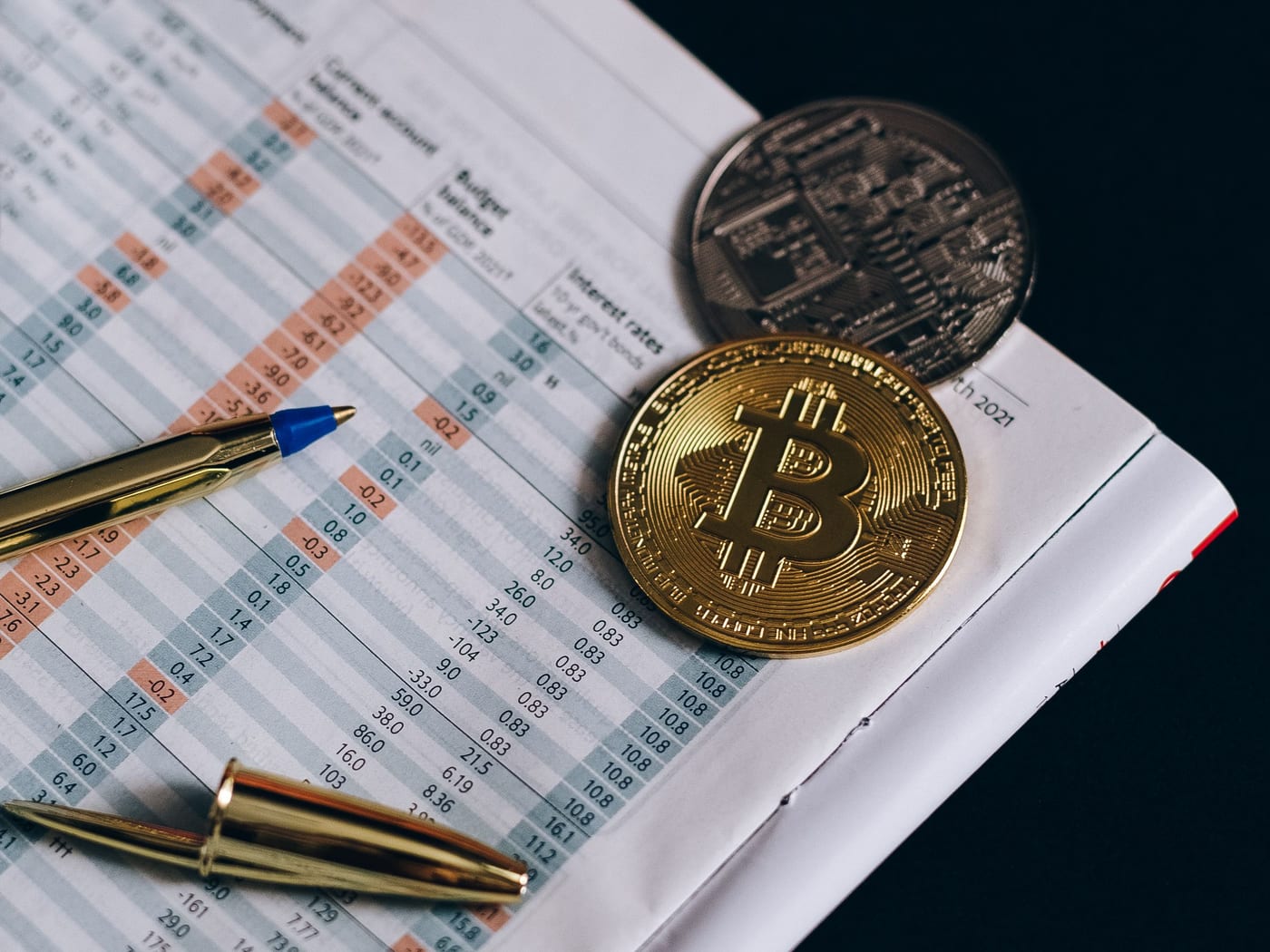Finanzunterlagen mit Zinstabellen, Kugelschreiber und Münzen